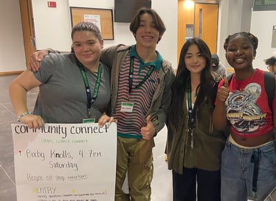 4 IVA Students stand together and show a poster for community connect event