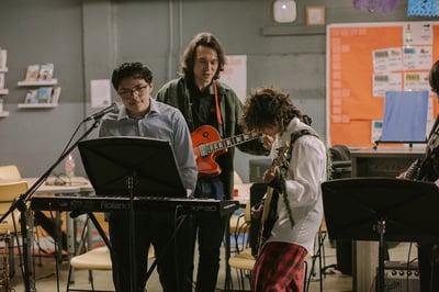 2 IVA students and IVA teacher play instruments together in a band