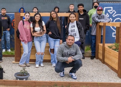 IVA Students standing around 3 raised garden beds planted with herbs and flowers.