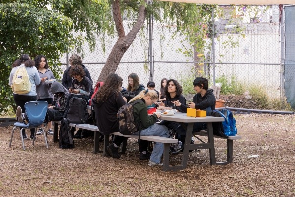 IVA students eating lunch at picnic table in backyard of school