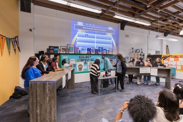 IVA students behind 2 tables at front of The Commons with 3 students in between tables.