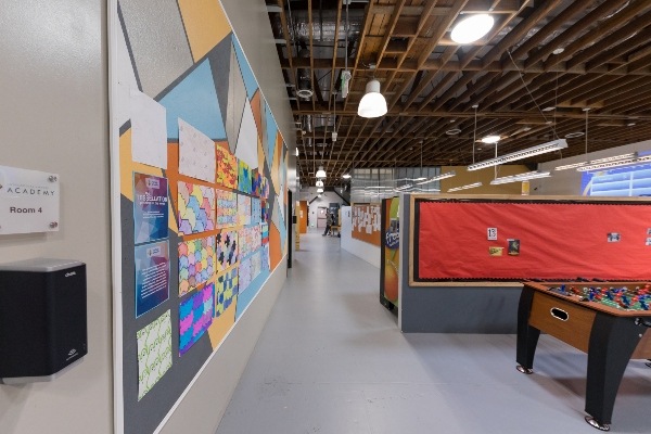 View of hallway at IVA High with colorful walls on left, half wall to the right and foosball table.